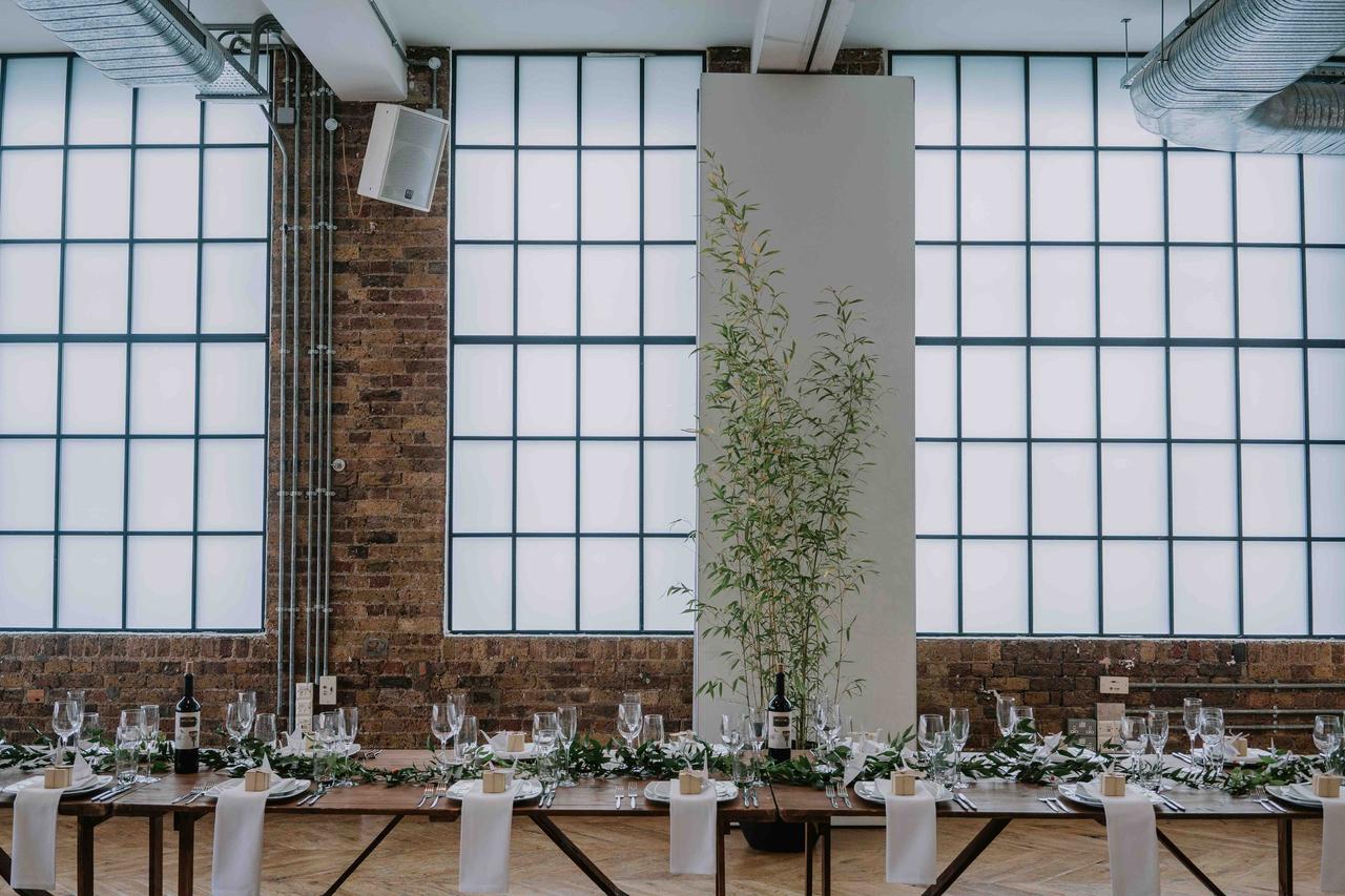 The tables set up banquet style with candles and foliage