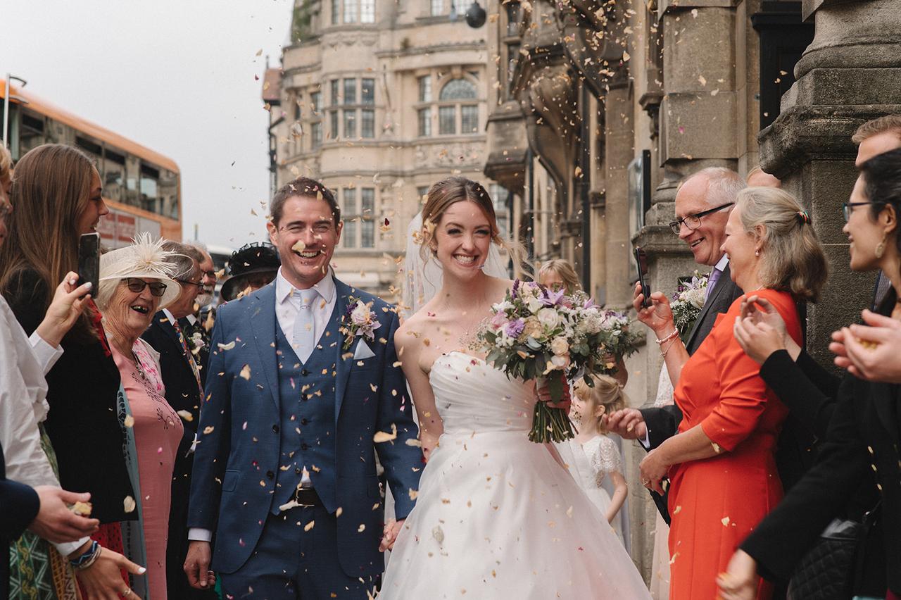 Bride and groom leaving ceremony with confetti being thrown over them
