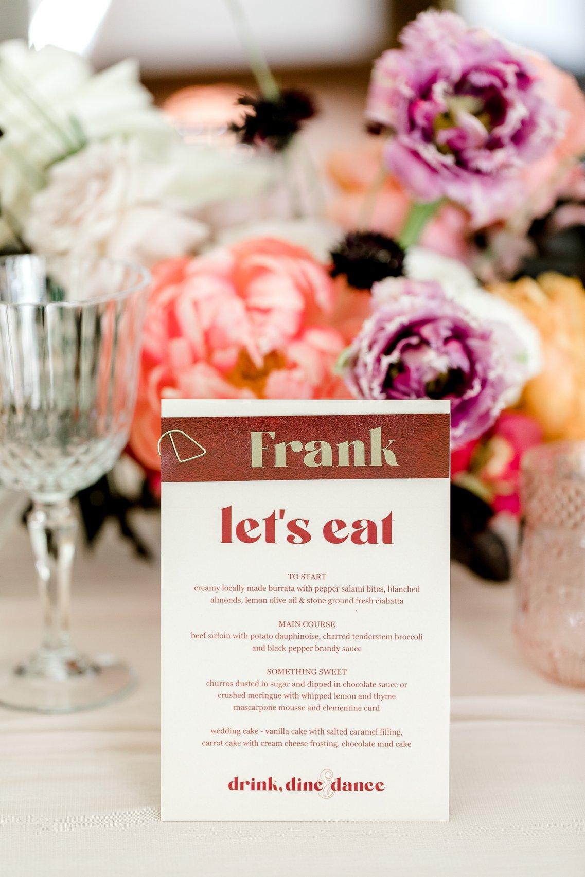 A close up of the wedding food menu printed on white card with burgundy text