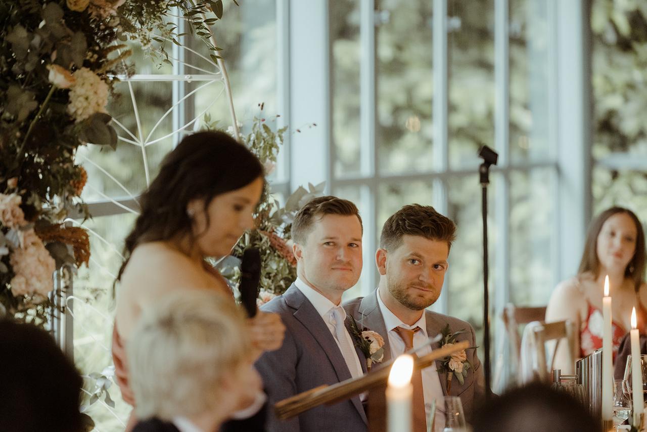 The grooms watch as a member of the wedding party makes a speech