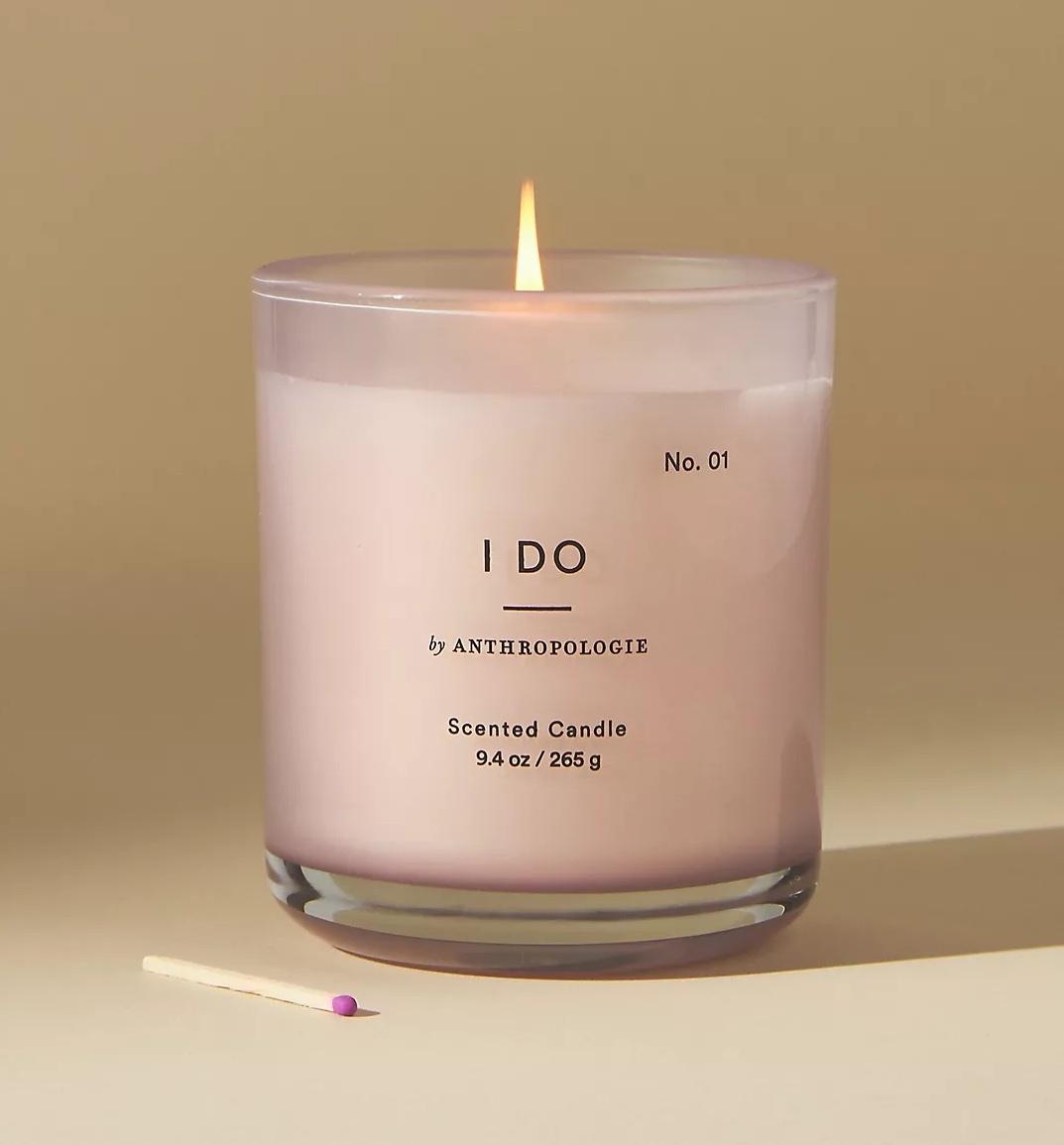 A pink candle in a clear glass holder that reads 