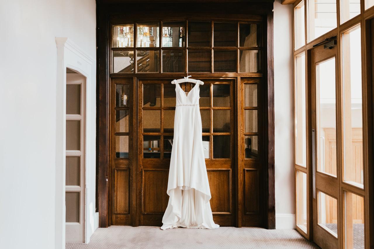 A wedding gown hanging on a wooden doorway
