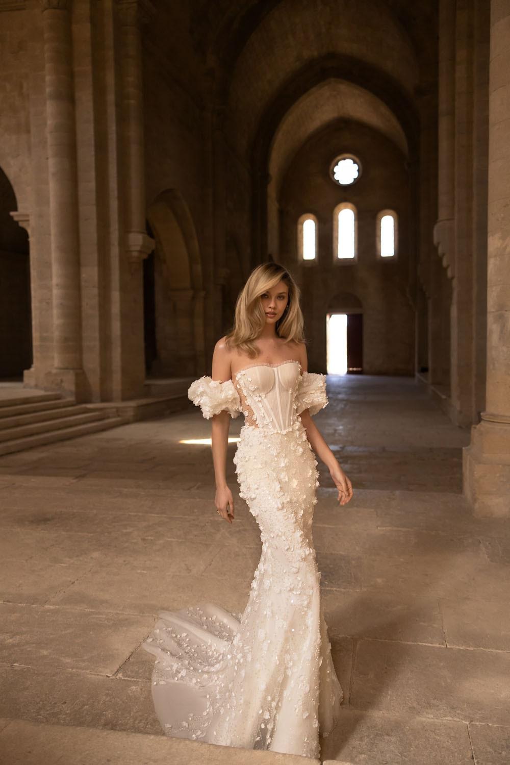 bride standing in old stone building wearing a 3d appliqué wedding dress with floral puff sleeves