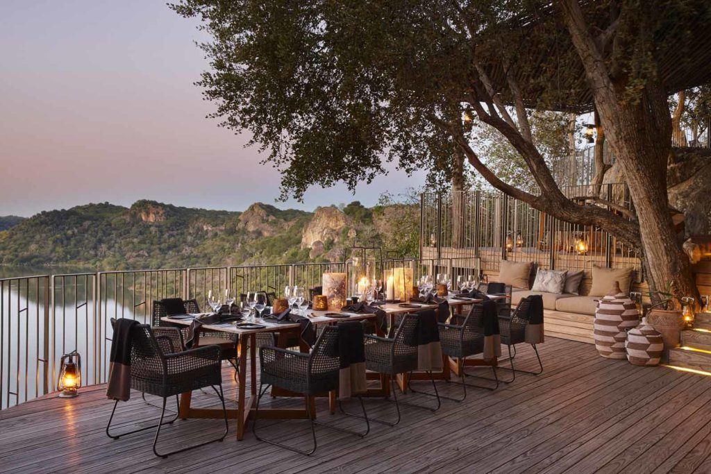 A glamorous table set for dinner on an outdoor terrace overlooking the African Bush, part of Malilangwe Wildlife Reserve