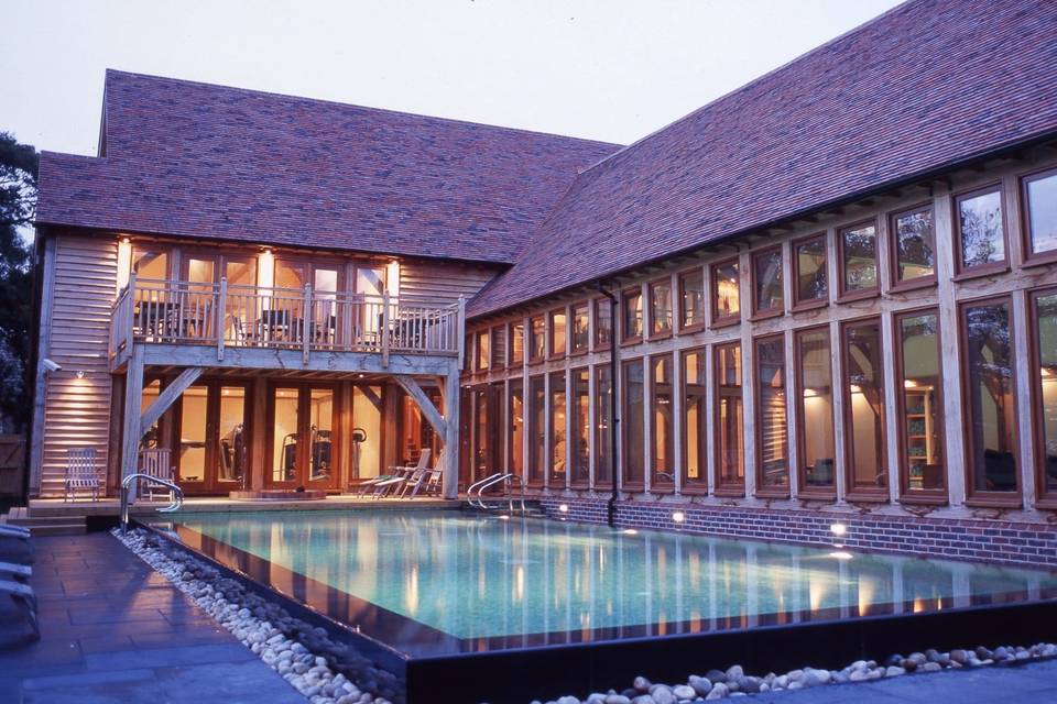 An outside view of the pool and building at Baliffscourt Hotel and Spa lit at dusk