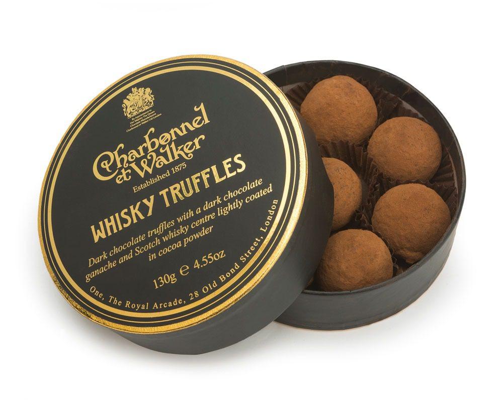 A round black and gold box of whisky truffles dusted in cocoa.