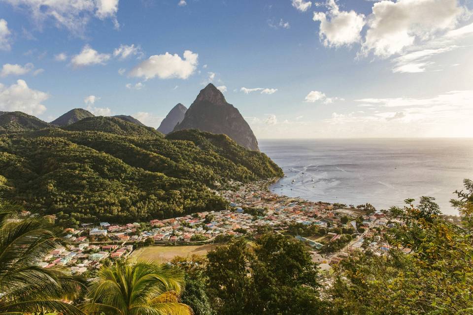 Aerial view of Saint Lucia with the Pitons in the background, and a collection of resorts scattered across the coast