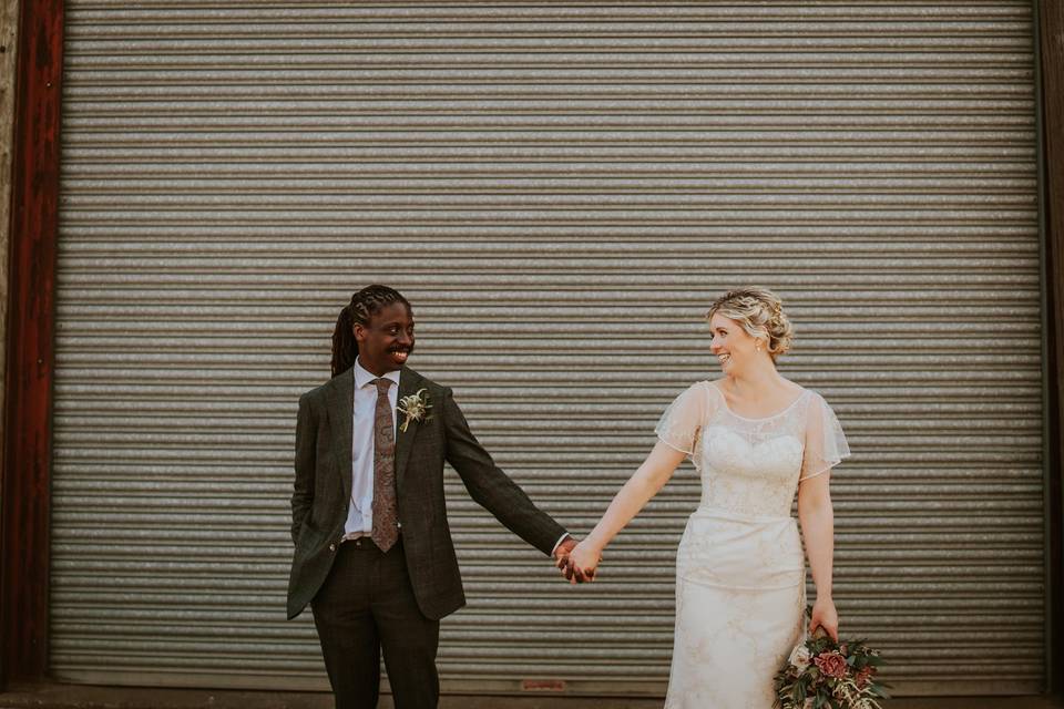 A bride and groom hold hands and look at each other