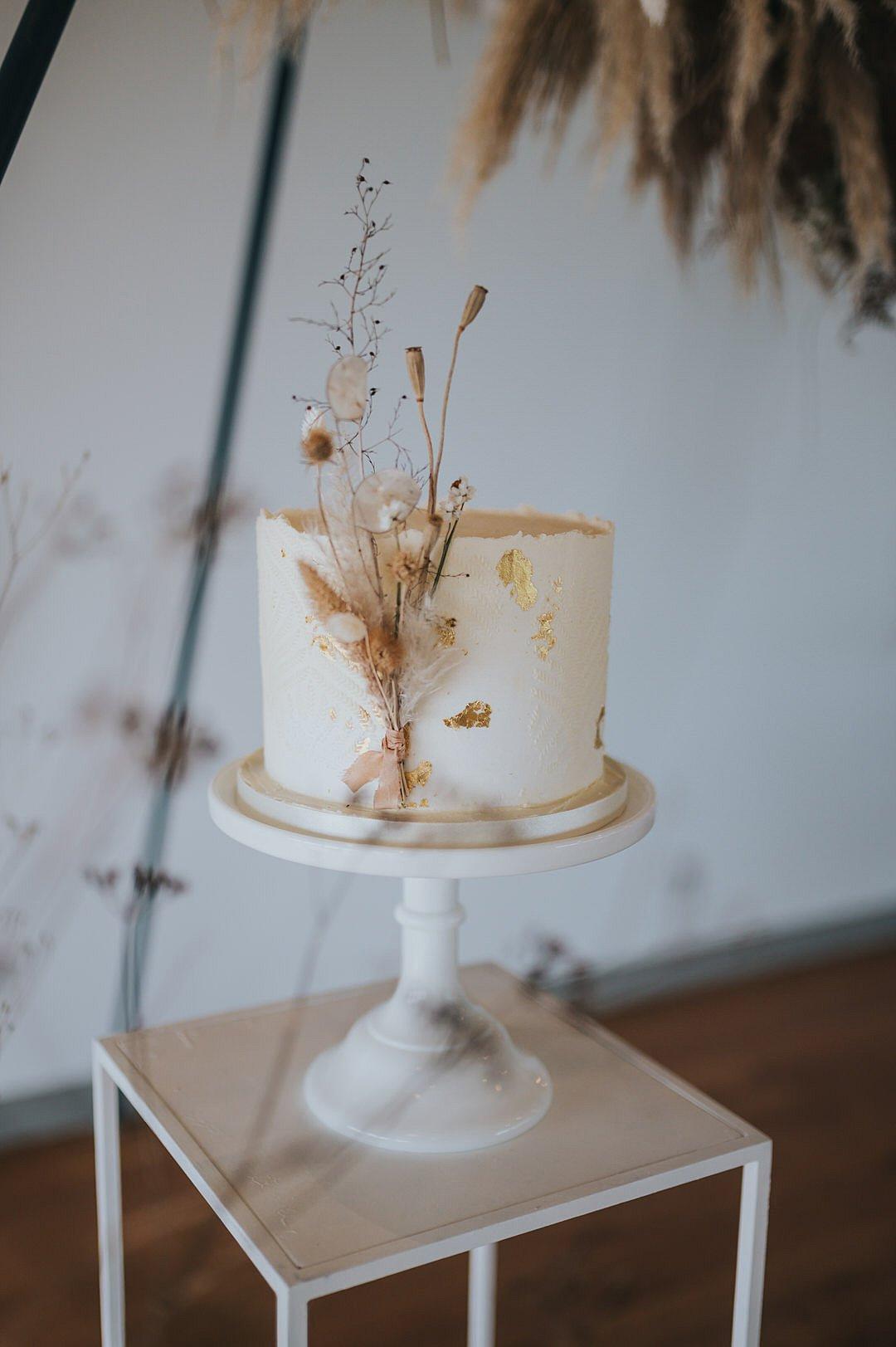 Single tier rustic wedding cake with neutral dried foliage