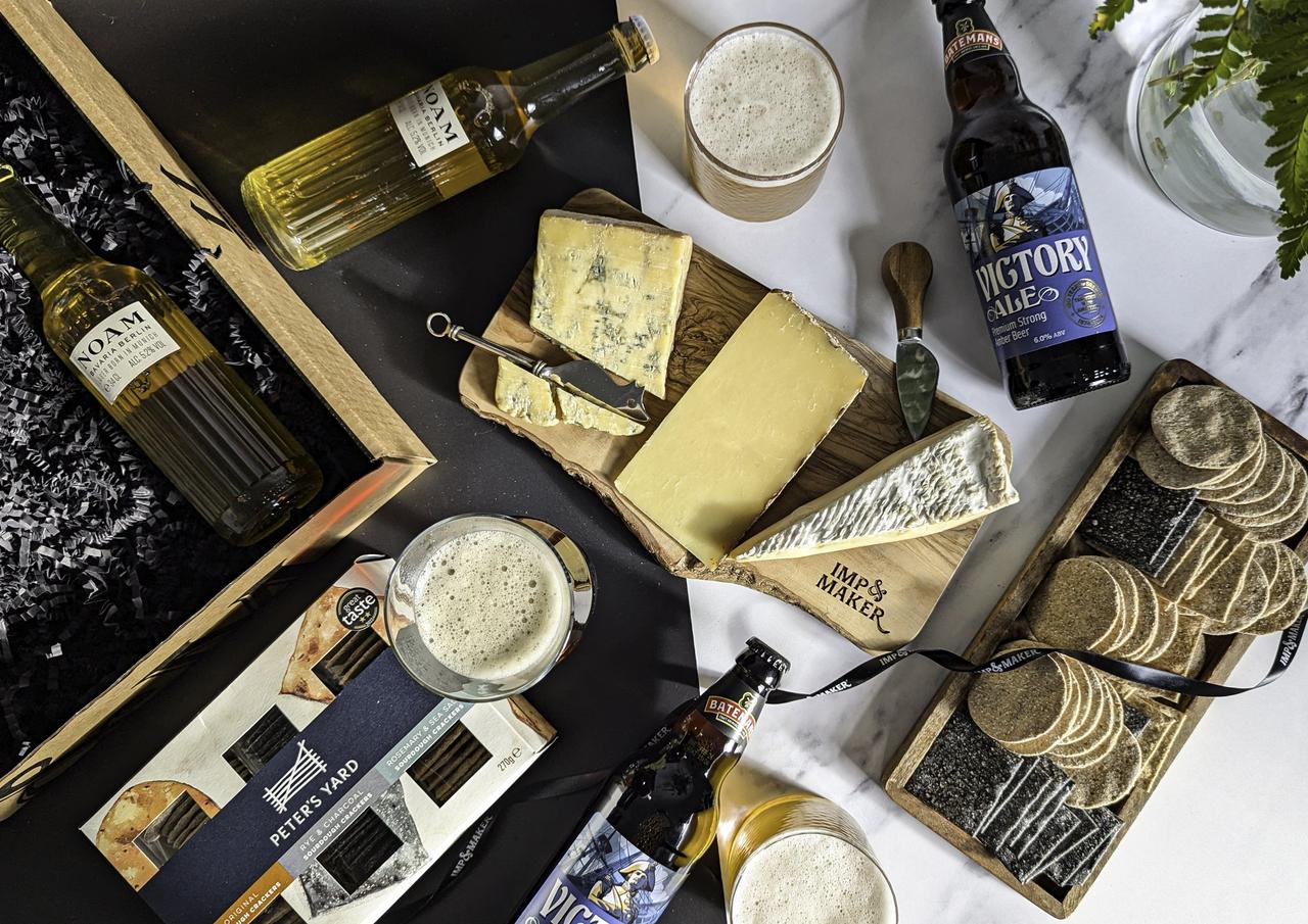 A flat lay of an open cheese and beer and ale hamper, a gift idea for a best man or groomsmen.