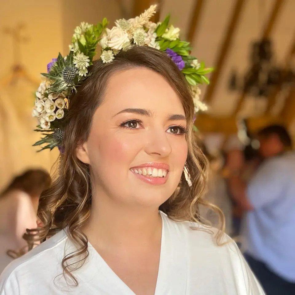 Smiling bride looks into the distance wearing a flower crown with curled hair