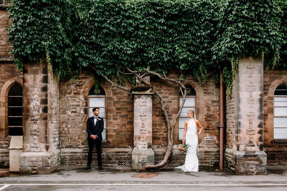 Bride and groom pictured against a brick wall