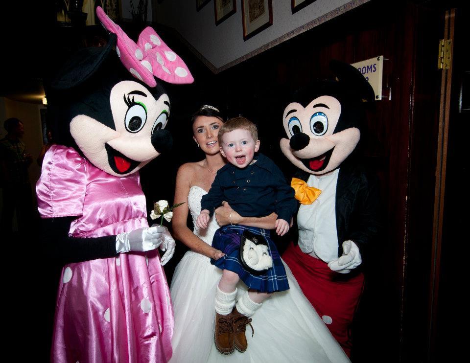 A bride and a child posing with children's wedding entertainers dressed up as Mickey and Minnie Mouse