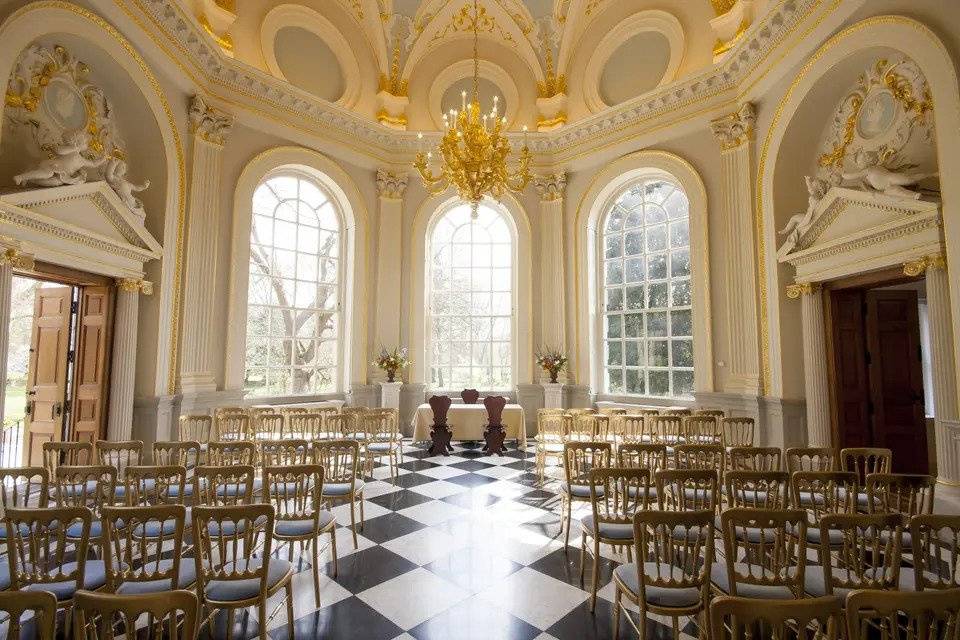 Octagonal room with gilded ceiling, floor-to-ceiling windows, tiled floors, gold chairs and gold chandelier