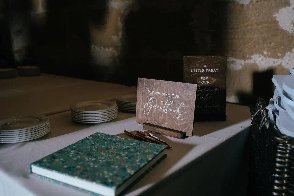 Blue floral guestbook on a table beside a sign saying 