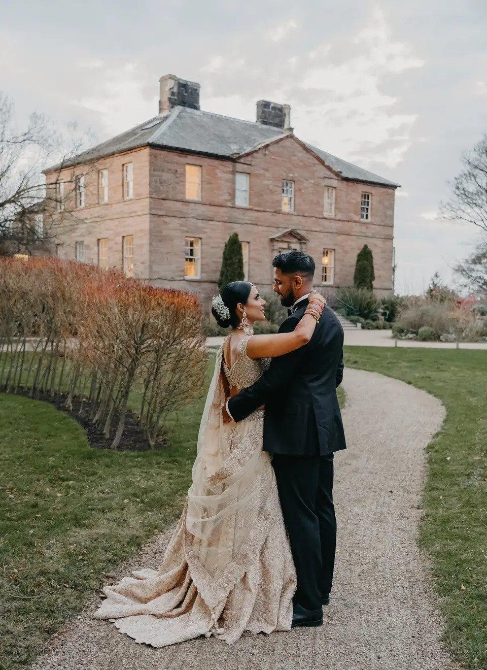 Asian bride and groom looking at each other outside a stately home style wedding venue in the north east of england