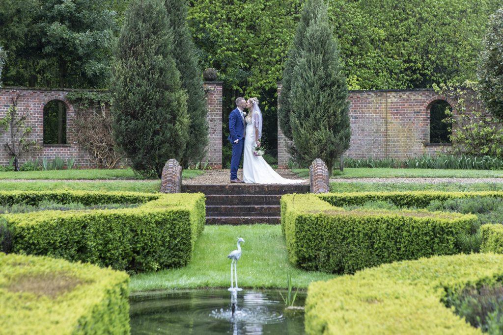 Bride and groom kissing in the gardens of Hertfordshire wedding venue Burloes Hall