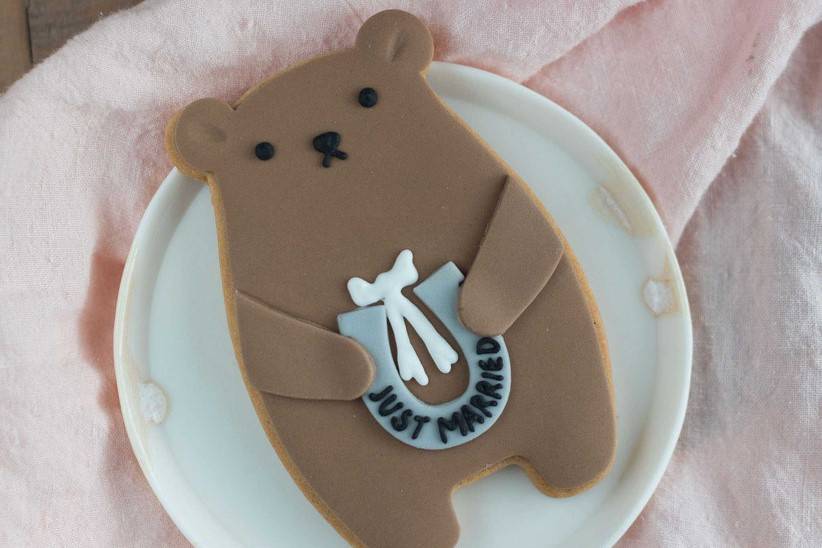 A children's wedding favour idea in the form of an adorable iced bear biscuit holding a horse shoe reading 'just married'