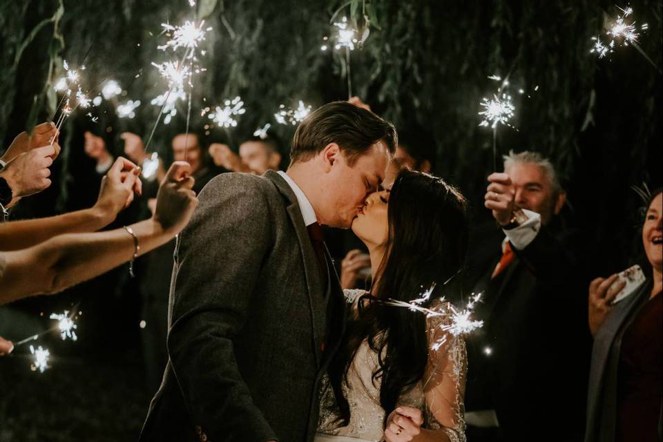Bride and groom kissing with sparklers on their wedding day
