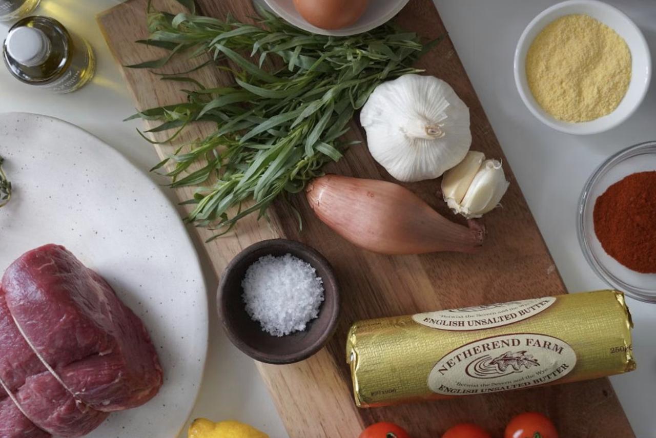 raw steak at home next to fresh herbs butter and spices