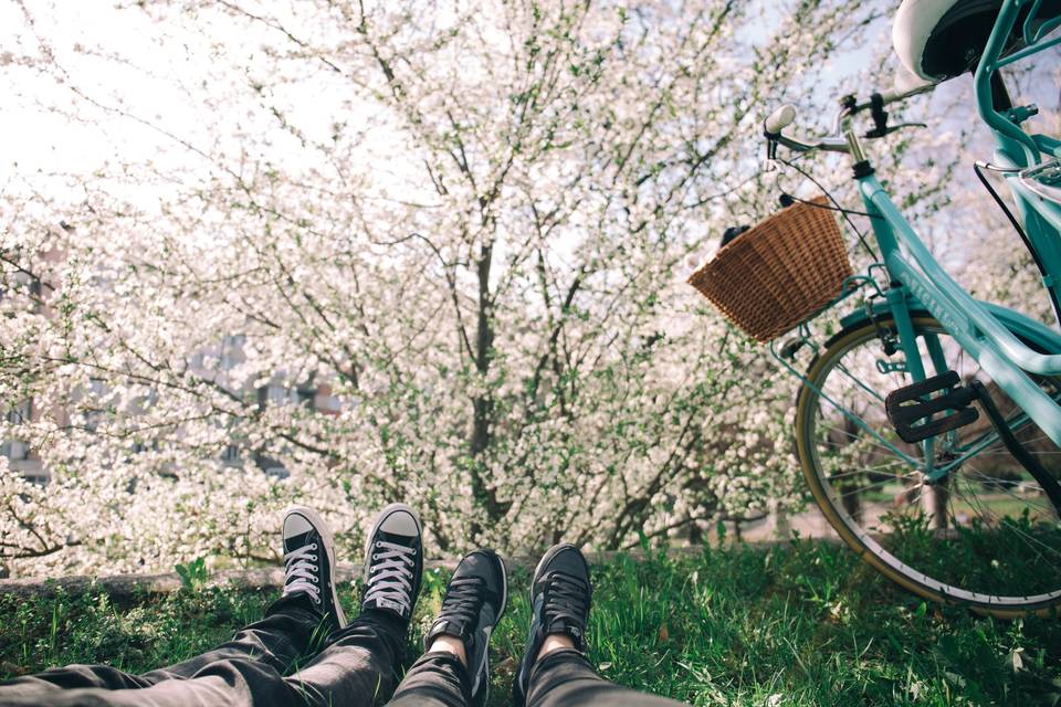 Shot of couple's legs lying on grass with both wearing trainers next to a blue bike