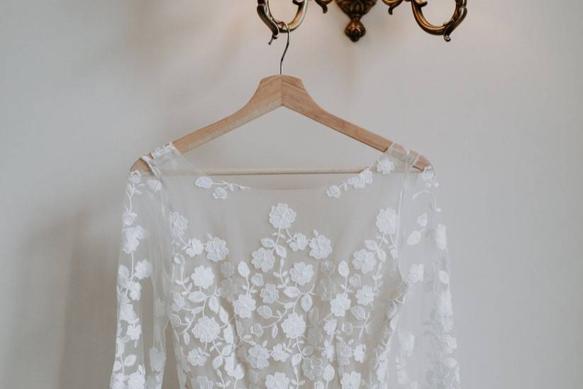 Long-sleeve lace wedding dress hanging up on a bridal hanger