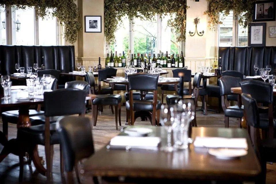 Function room with laid tables, wine bottles and hanging plants