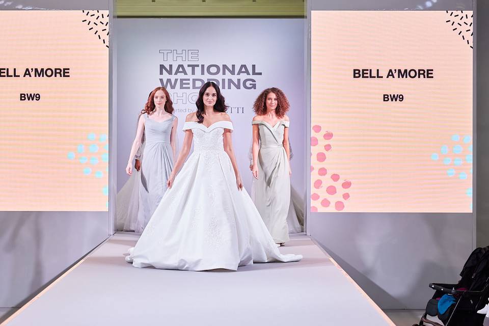 three models in wedding dresses on the runway at the national wedding show