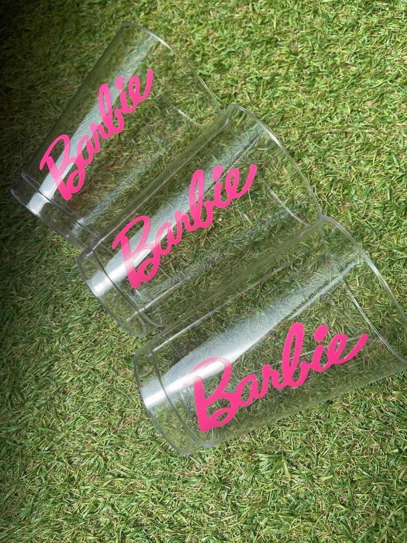 Three clear plastic cups with Barbie written in hot pink text