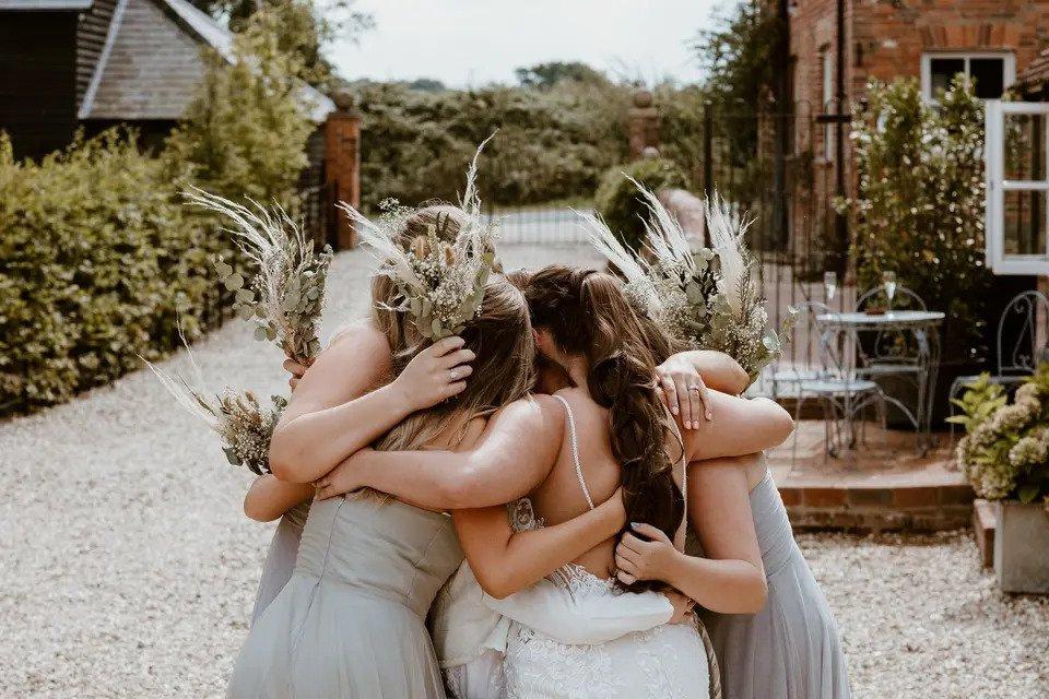 A bride and her bridesmaids huddled together in a close group hug