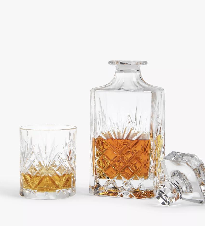 crystal glass decanter full of whiskey next to glass tumblers