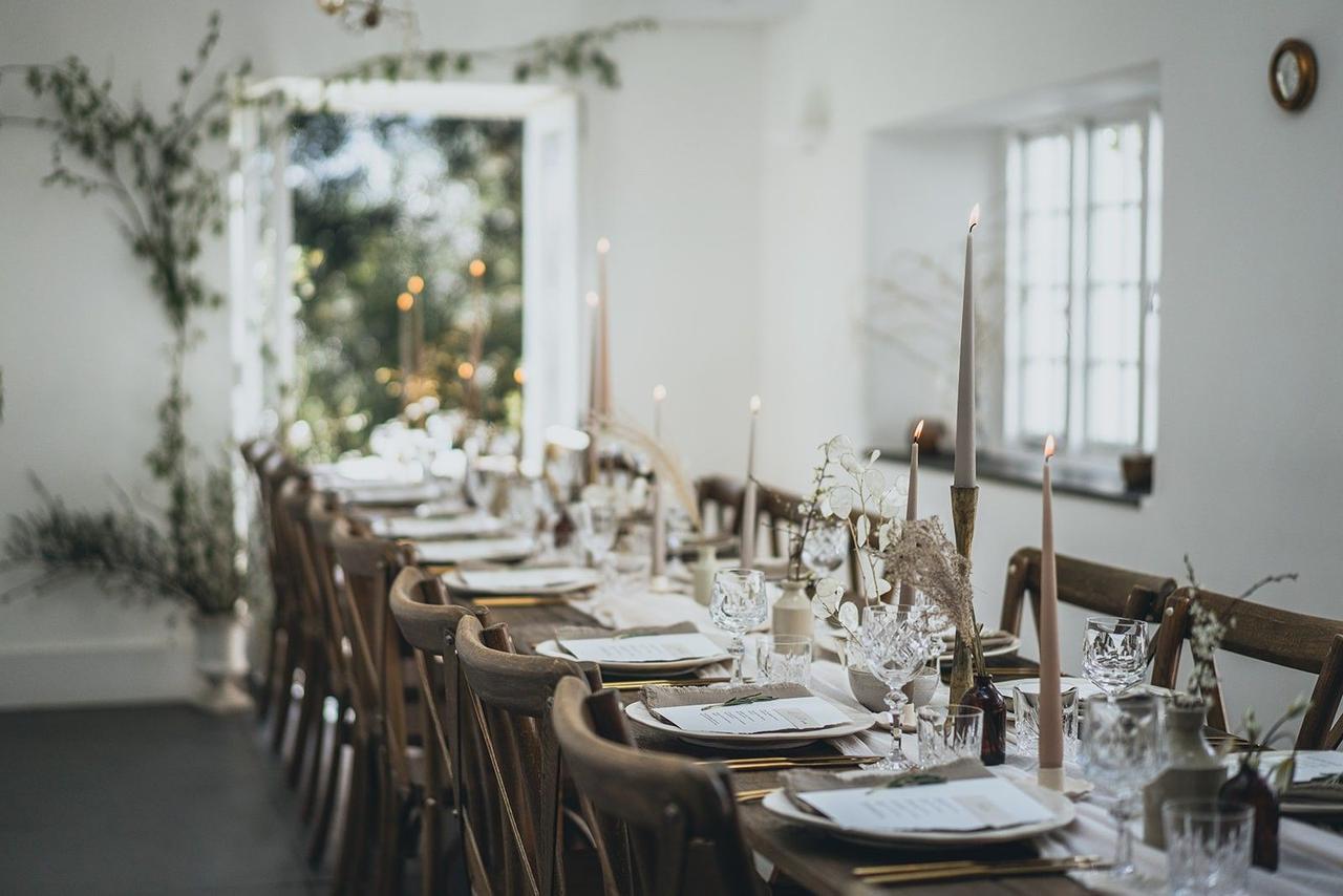 A rustic dark wooden table set up with botanical decorations and cream places in Tresen wedding venue