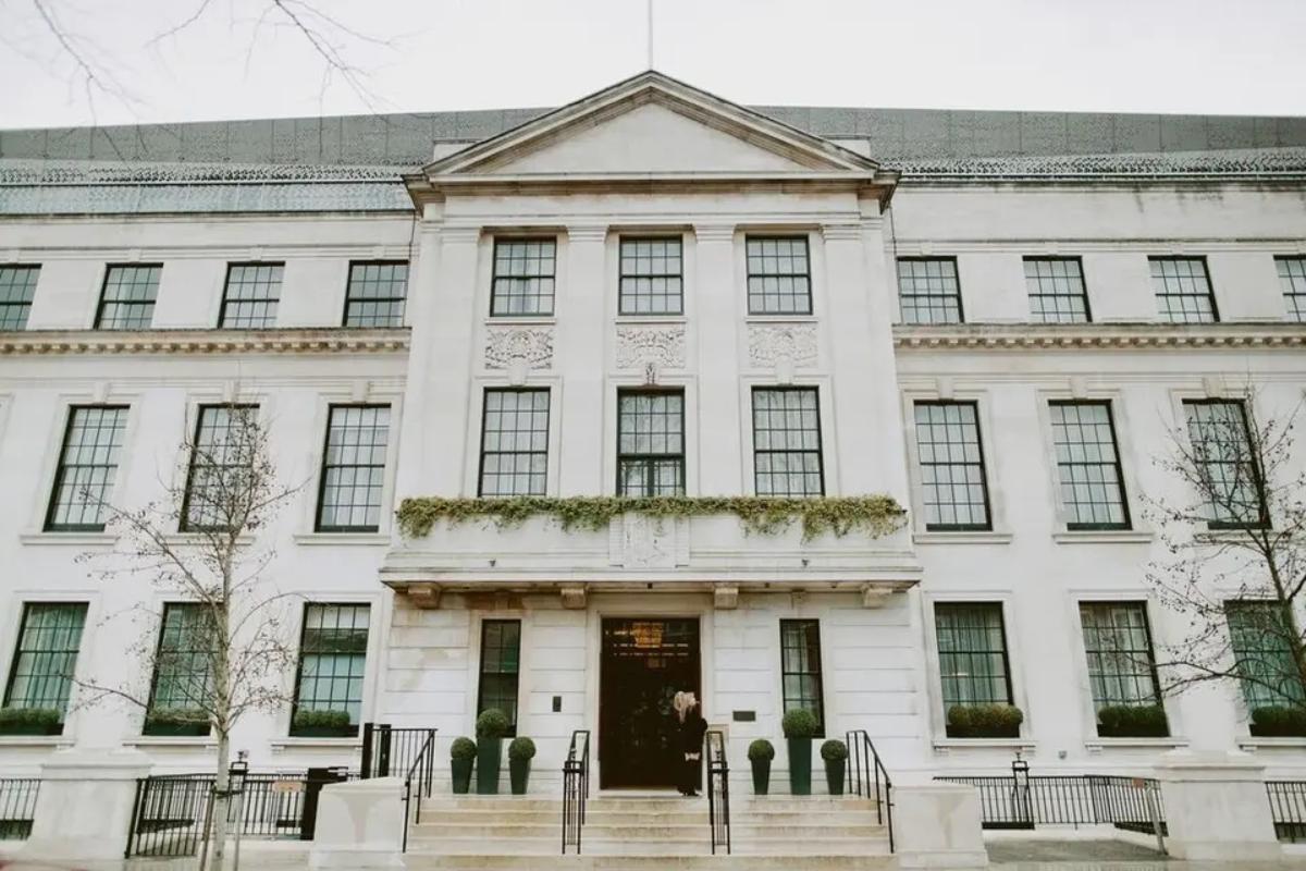 a chic white building with a brown door in the middle and steps leading up to the entrance 