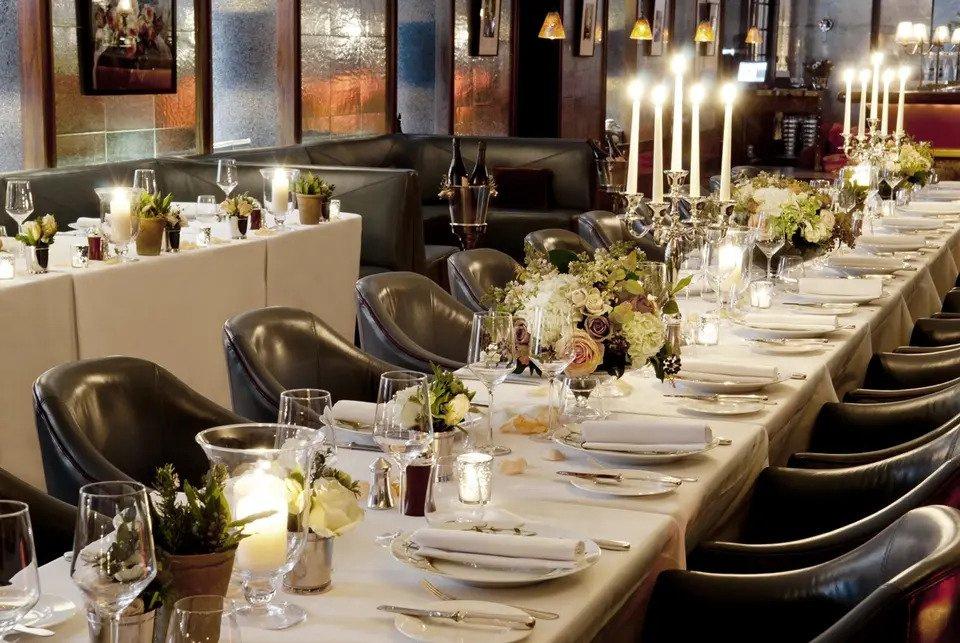 Long table laid for meal with dinner candles and floral centrepieces