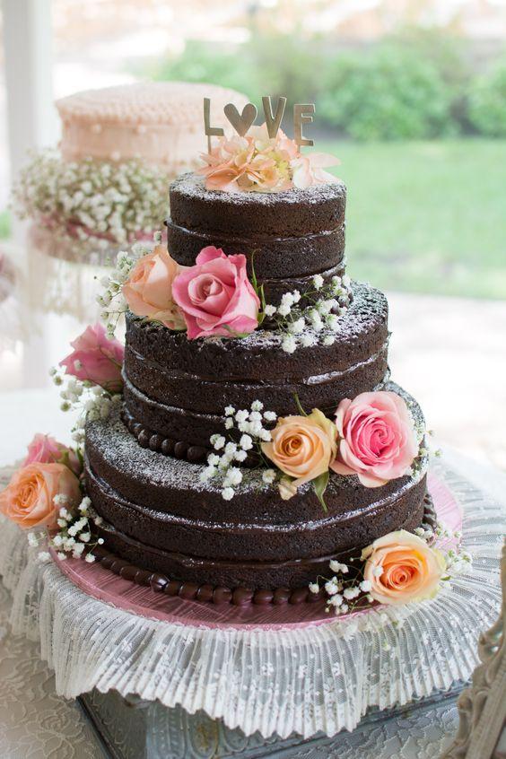 Three tiered naked chocolate rustic wedding cake with flowers