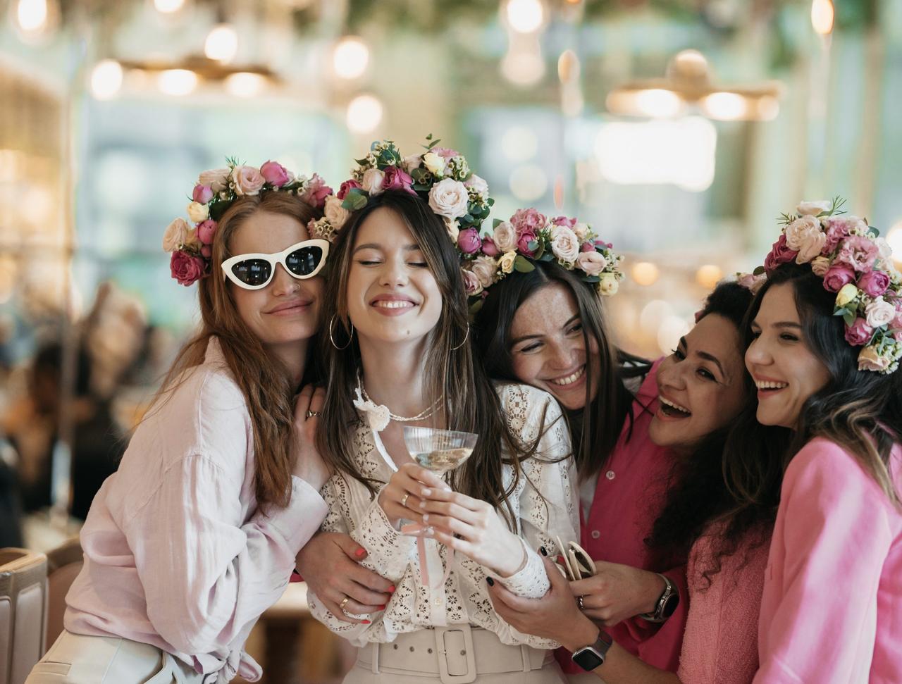 Five girls huddled together wearing flower crowns on a hen do.