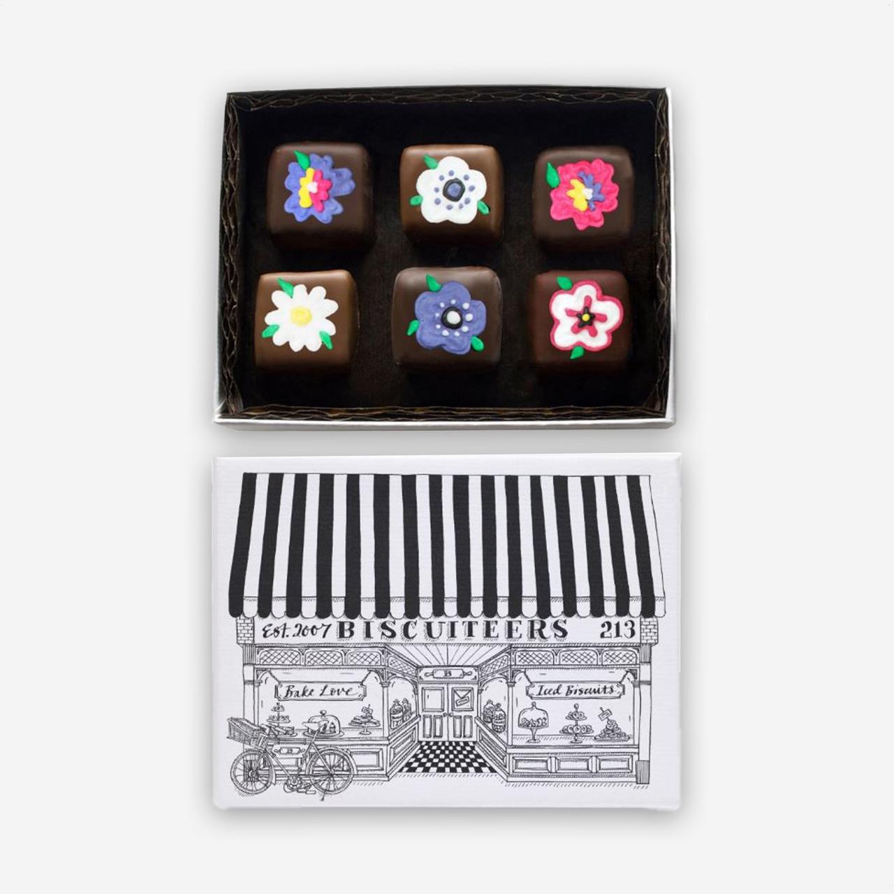 An open box of hand-iced chocolates decorated with icing flowers.