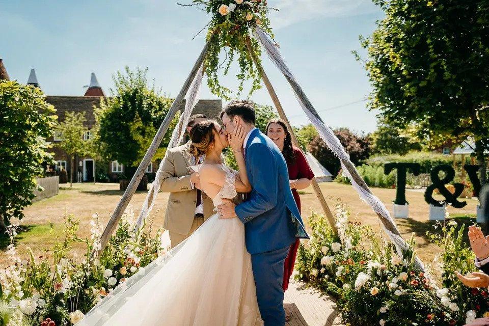 Bride and groom kiss at the altar at an outdoor wedding ceremony near a red brick wedding venue