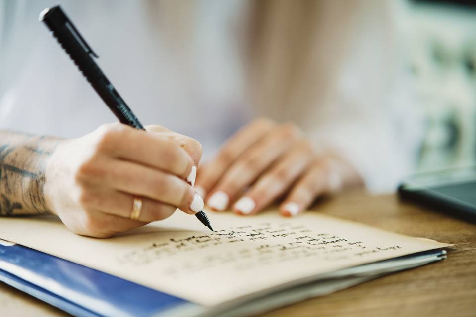 a handwritten letter being written at a desk with an ink pen