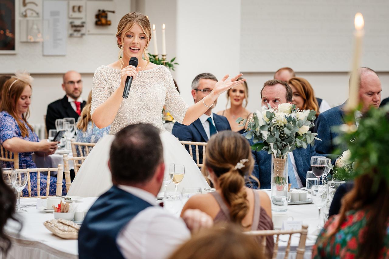 A bride giving a speech at her wedding reception.