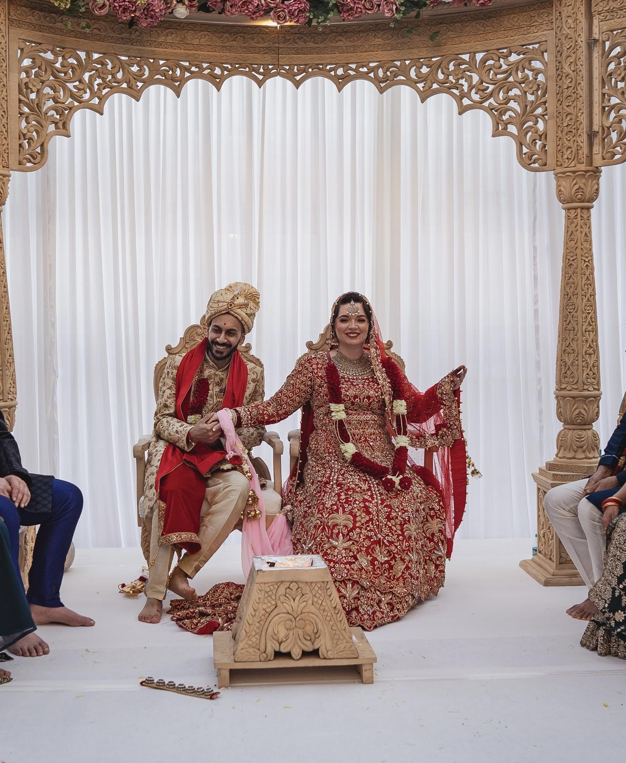a bride and groom sat together at their wedding dressed in red and gold