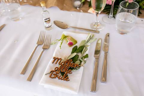 A rose gold Mother of the Pride place name on top of a napkin on a wedding table
