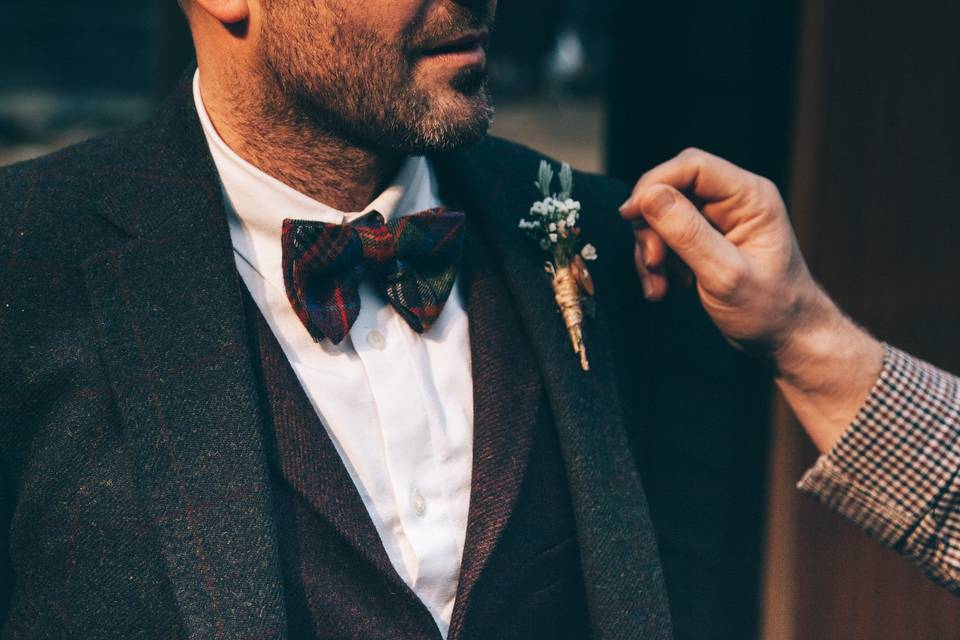 Man in checked suit adjusting his best man's buttonhole