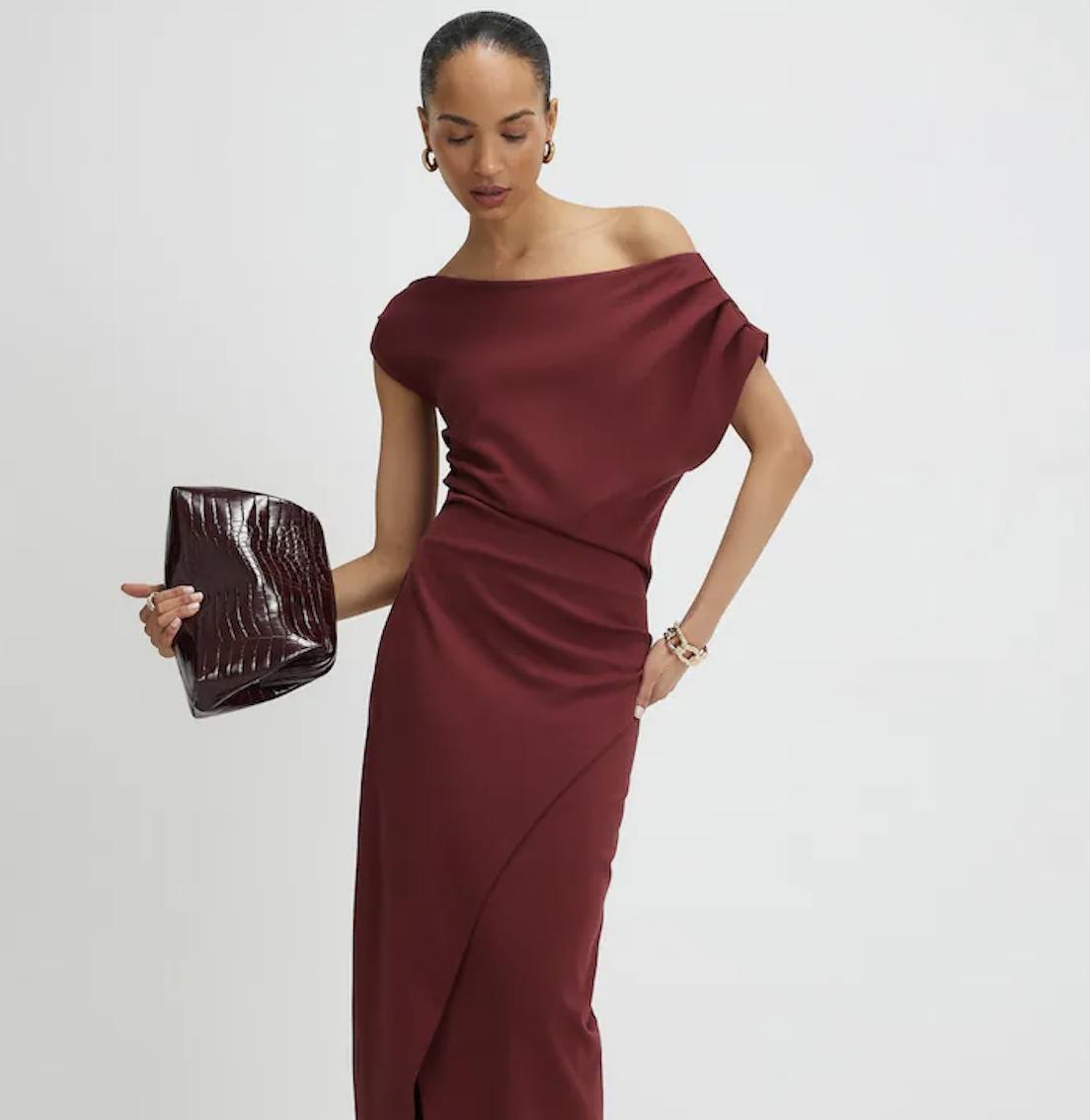 model with slicked back hair wearing an off shoulder dark maroon dress