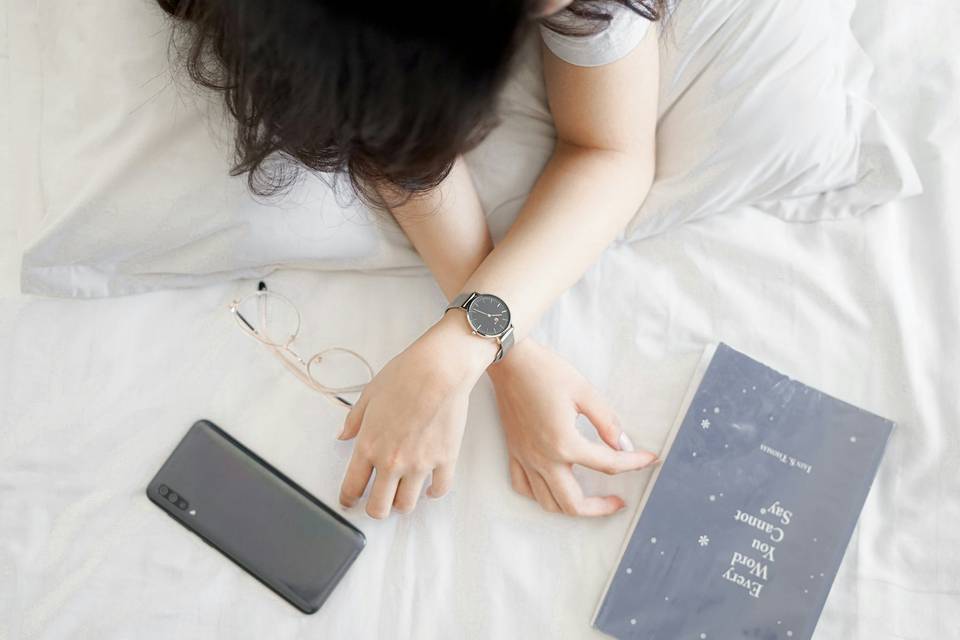 girl lying in bed with a mobile phone and a book of poems