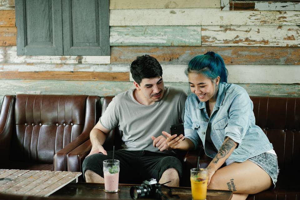 Man with facial hair and woman with blue hair looking at a mobile phone together as they use a free wedding planning app
