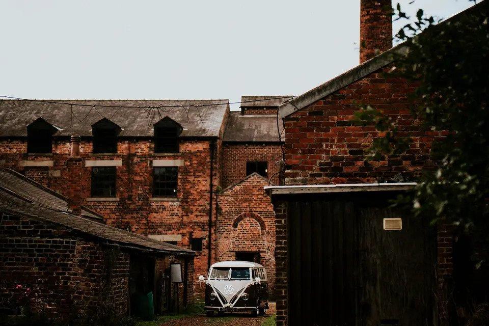 Red brick exterior of Thwaite Watermill with VW campervan parked outside