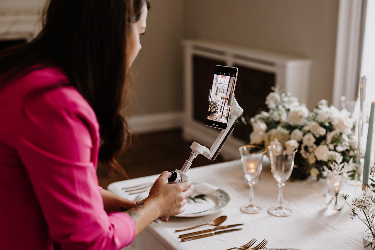 A wedding content creator recording a tablescape on a mobile phone