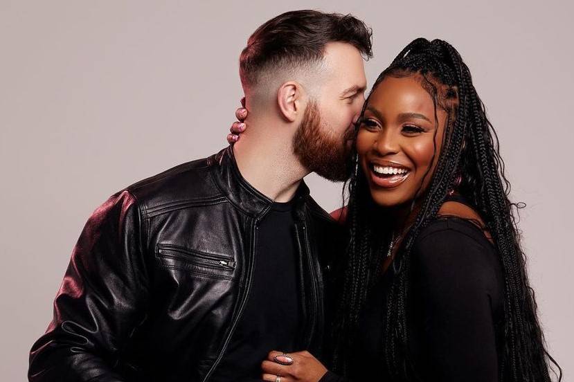 love is blind couple cameron and lauren kiss on the cheek and smile against a white background