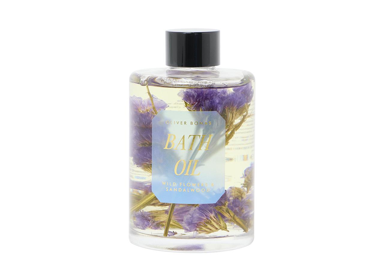A bottle of bath oil with wildflowers and sandalwood inside.